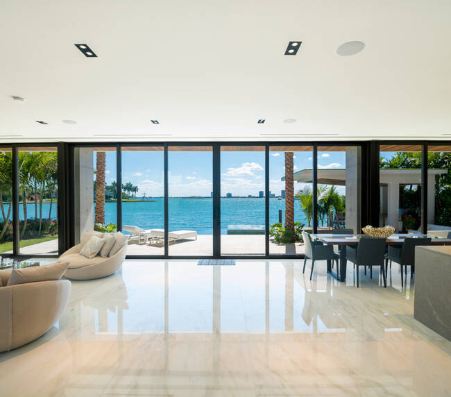 Miami Beach - April 2019: Modern living and dining areas with wide views of the bay and city. Beautiful minimalist white interior